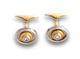 83.  Gemelos circulares con brillante de 0,10 ctes aprox y marco ovalado en en oro bicolor de 18k.