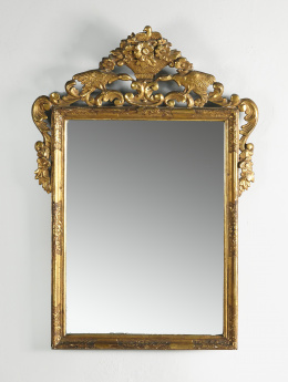 827.  Espejo de madera tallado y dorada, rematado por un copete con un cesto de flores y dos aves enfrentadas. Trabajo español, S. XVIII.