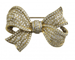 444.  Broche lazo cuajado de brillantes con sutiles líneas caladas, en oro amarillo de 18K