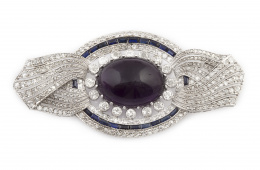 591.  Broche Eduardino en forma de lazo de diamantes con gran cabuchón de amatista central, orlada de chatones de brillantes de talla antigua y óvalo exterior de zafiros calibrados y brillantes 