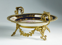 349.  Plato de porcelana montado en metal dorado y esmaltado en azul “Real” y dorado;  decorado con cartela central con escena pastoril y flores en el alero. Marca estampada del “Chauteau Des Tulleries”, “Sévres 1844”.Sévres, 1844.