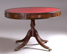 571.  Mesa de “tambor”o “Drum table” sobre pata central en madera de caoba con tapa de piel en color rojo.Trabajo inglés pp. S. XX.