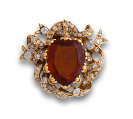 621.  Broche portugués s.XIX con corazón de topacio Imperial de 25 ctes aprox rodeado por cintas entrelazadas de brillantes de talla antigua.