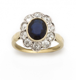 120.  Sortija con zafiro oval de 1.20 ct aprox orlado de brillantes, en oro de 18K con frente de oro blanco.