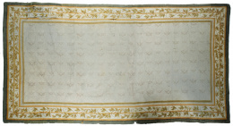 1052.  Alfombra en lana de nudo español, de color beige y cenefa con flores.