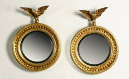 1007.  Pareja de espejos convexos “Regency” de madera tallada y dorada, rematadas por un de águila de bronce.Trabajo inglés o americano, primera mitad del S. XIX.