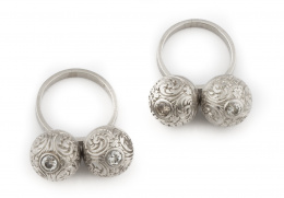 653.  Sortija de platino con dos esferas colgantes decoradas con roleos y con chatones de brillante central