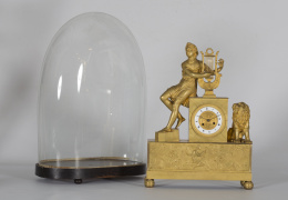 532.  Reloj de sobremesa en bronce dorado. Sobre basamento rectangular, con escena de la vida de Orfeo. Encima, esfera de porcelana sobre fondo de bronce. Sentada sobre ella, la figura del dios.Francia, primer tercio del S. XIX.