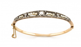 663.  Brazalete rígido de pp s.XX con centro de diamante de talla holandesa, entre líneas de perlas finas y diamantes talla rosa dentro de marcos calados.