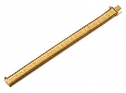 90.  Pulsera articulada años 50 con banda central de oro mate con decoración grabada entre dos líneas de cadenetas