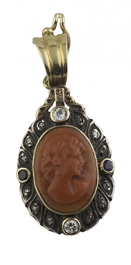 17.  Colgante de camafeo tallado en coral de pp. S. XX con busto de dama; rodeado por marco adornado con dos brillantes de talla antigua, dos zafiros y diamantes entre ellos