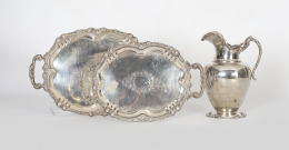 1006.  Dos bandejas ovales de plata con contorno de flores y cintas, con marcas.Mediados del S. XX. .