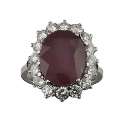165.  Sortija con rubí oval de 7 ct. aprox. orlado de brillantes, en montura de oro blanco de 18K con galería calada