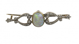 117.  Broche de pp.S.XX con cabuchón de ópalo central enmarcado por dos piezas en forma de lira de brillantes
