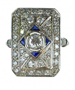 125.  Sortija lanzadera rectangular estilo Art-Decó de brillantes, con un brillante en chatón central y y cuatro zafiros que forman marco de rombo 
