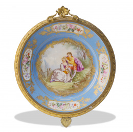 593.  Plato de porcelana esmaltada en azul con escena a la manera de "Watteau", montado en metal dorado. Con sello en el reverso.Sévres, 1873.