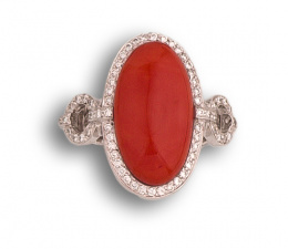 153.  Anillo con gran cabujón de coral central orlado de brillantes, y con dos aros de brillantes que lo unen a los brazos de la montura.