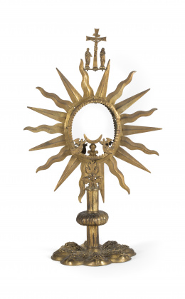 534.  Custodia de sol de metal dorado con pie polilobulado y aplicaciones de cabezas sobre hojas de acanto , rematado por una crucifixión.Trabajo español, S. XVII, con elementos posteriores..