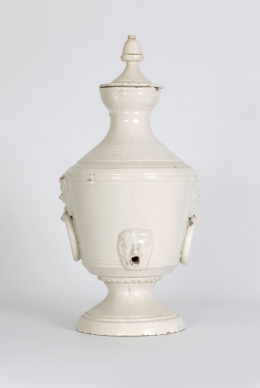 1179.  Aguamanil de cerámica esmaltada de blanco con argollas a cada lado y cabezas modeladas.Alcora, S. XIX.