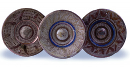 1125.  Tres platos esmaltados de reflejo metálico y azul cobalto.S. XVI - S. XVII.
