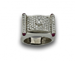 722.  Sortija estilo chevalière con pavé de brillantes en torno a btes en chatón central y rubíes en los extremos.