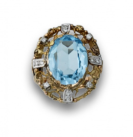 768.  Sortija con topacio azul ovalado en marco calado, con brillantes de oro bicolor de 18K.