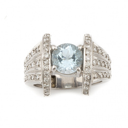 314.  Sortija con topacio azul de talla redonda entre brazos a modo de ménsulas de brillantes, en oro blanco de 18K
