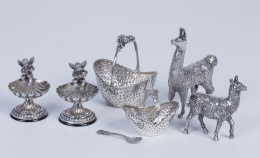 1219.  Lote de siete piezas de plata, dos llamas, dos saleros rematados por angelitos, dos cestitas y una cucharita, S. XX.