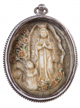 513.  Medalla devocional de la Virgen de guadalupe de marfil tallado, dorado y plocromado. Marco de plata en su color, rematado a cordoncillo.Trabajo mejicano, S. XVIII
