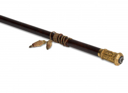 637.  Bastón de mando en carey y empuñadura en oro decorada con personajes armados y escudos, rematada por un círculo de brillantes. Con borla en hilo dorado y rojo.