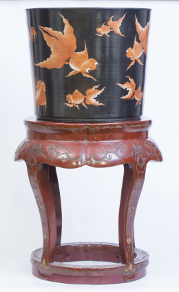 1063.  Pecera en porcelana esmaltada con decoración de peces, sobre peana en madera lacada con decoración floral