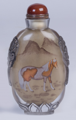 1131.  Snuff bottle pintada bajo cristal decorada con un caballo en un paisaje, laterales en relieve y base con hoja de loto. Firmada.Ding Erzong (1868-1935)  Trabajo chino.