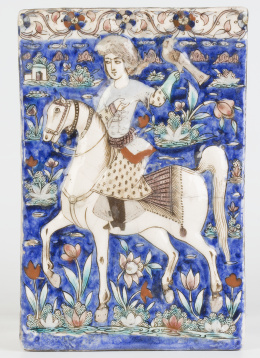 634.  Azulejo en cerámica esmaltada en azul cobalto, en el que se representa un príncipe a caballo con un halcón sobre fondo azul, en un fondo de floresPersia, dinastía Qajar S. XIX