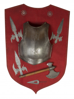 1132.  Panoplia, con un escudo, cuatro puntas de flechas y un hacha, en acero grabado.Trabajo español, posiblemente trabajo toledano ffs. del S. XIX