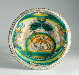 1245.  Lebrillo de cerámica esmaltada en verde ocre y amarillo sobre fondo blanco, representando a un ciervo en el asiento.Triana, S. XIX.