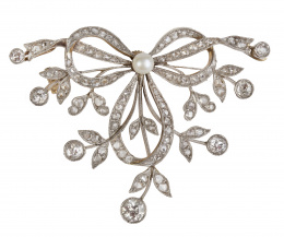 77.  Broche Belle Epoque con diseño de lazo y ramitas de diamantes rematadas en chatones de brillantes, con una perla fina central