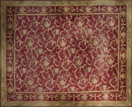 933.  Alfombra en lana de nudo español, campo granate y roleos de hojas en ocre.España, primera mitad del S. XX.