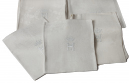 964.  Lote de 28 servilletas en hilo blanco con inicial "H" bordada bajo corona y decoración vegetal, flora y con perros, pp. del S. XX.