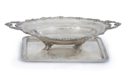 943.  Lote de frutero oval con asas en plata alemana ley 800 con borde de uvas y bandeja con borde de laúrea, pp del S. XX.