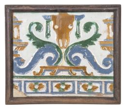 577.  Azulejo renacentista de arista con bucráneo y hojas en tornapunta, esmlatado en verce, azul y ocre.Triana, 1501-1600.