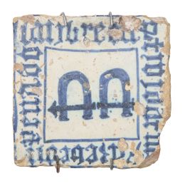 571.  Azulejo de cerámica esmaltada en azul y blanco con el escudo y leyenda alrededor.Valencia, S. XV.