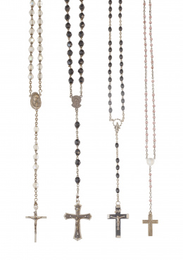 70.  Lote de cuatro rosarios con cuentas de diferentes materiales en plata y metal