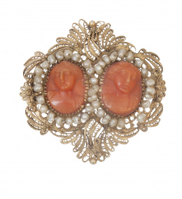 26.  Broche de pp. S. XIX con dos camafeos de damas tallados en coral, orlados de perlas finas en marco de filigrana de oro