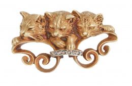298.  Broche Art Nouveau con tres gatitos apoyando sobre bandas de roleos unidas con arco de diamantes
