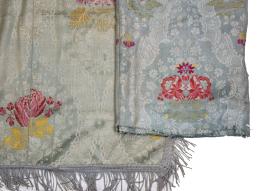 1222.  Lote de colcha en seda azul con flores bordadas en rosa y amarillo, rematada por flecos, y otro fragmento de seda azul con flores.S. XVIII.