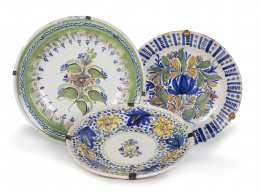 641.  Lote de tres platos de cerámica: dos de cerámica de Manises y uno de cerámica de Ribesalbes, esmaltado en azul oliva, S. XIX.