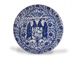 1112.  Plato de cerámica esmaltada en azul y blanco con águila bicéfala y escudo.Fajalauza, S. XIX.