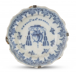507.  Plato de cerámica esmaltada en azul y blanco, con escudo de la orden de los Agustinos bajo capelo cardenalicio.Talavera, serie puntilla, h. 1750-1775.