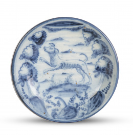 508.  Plato acuencado de cerámica esmaltada en azul de cobalto con perro entre árboles de pisos.Talavera, S. XVIII.
