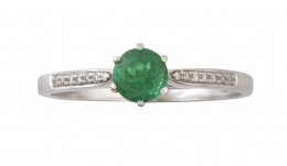 192.  Anillo en oro blanco con esmeralda central y brillantes a los lados en los brazos de la montura